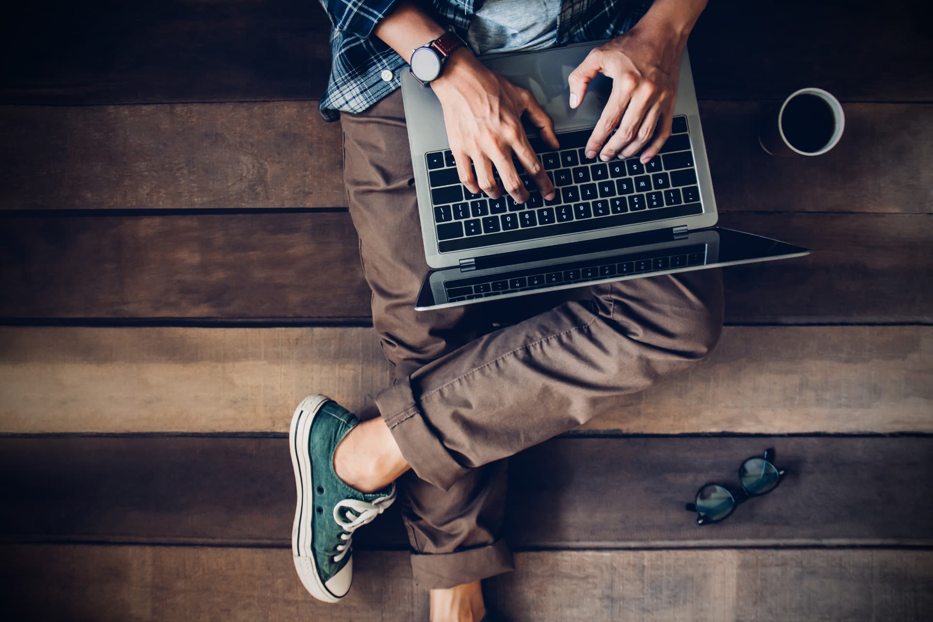 businessman sitting on wooden floor with coffee cup and glasses using laptop working at home to send and send reply to email Message customer service