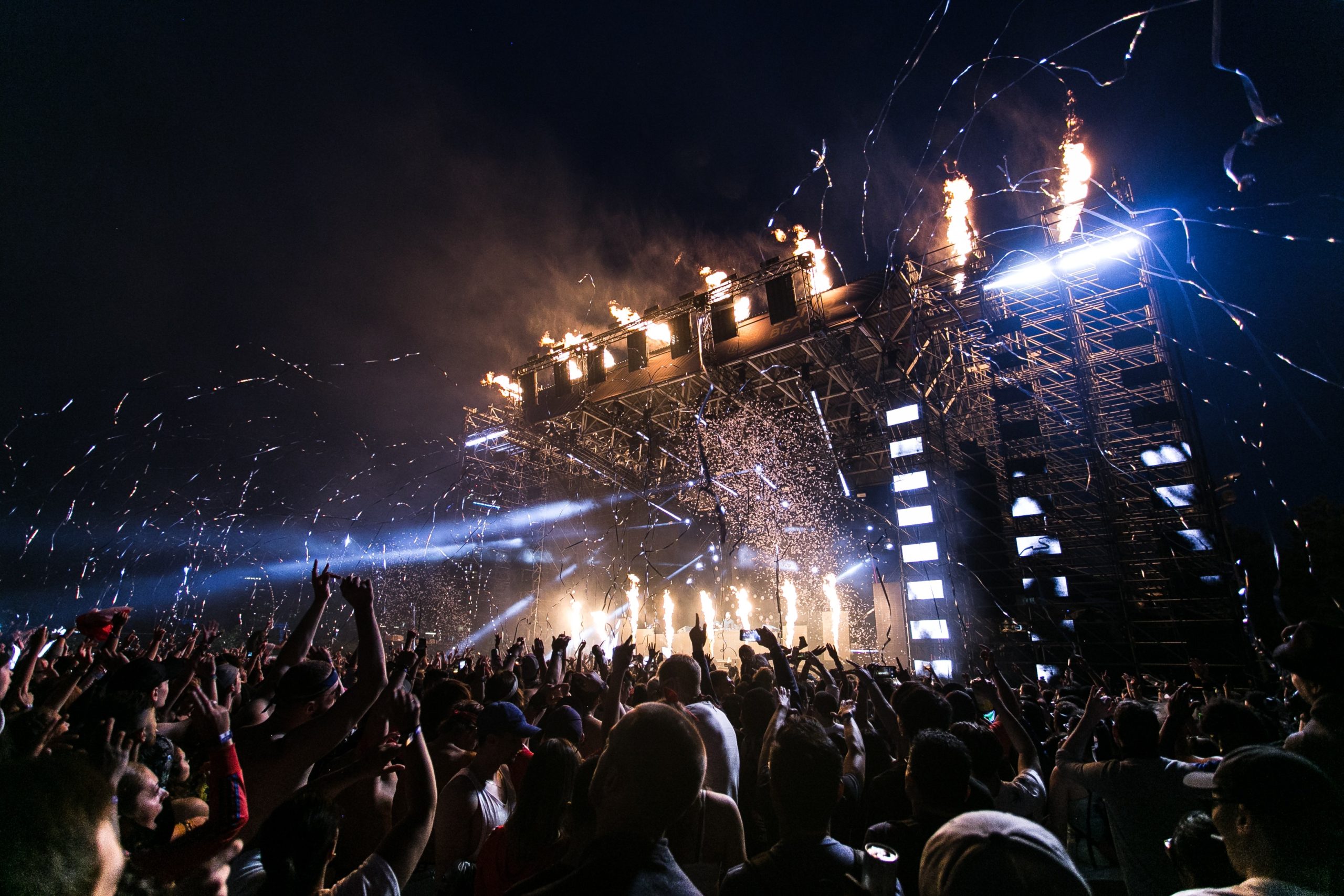 scène d'un concert la nuit, avec des confettis et le public mains en l'air
